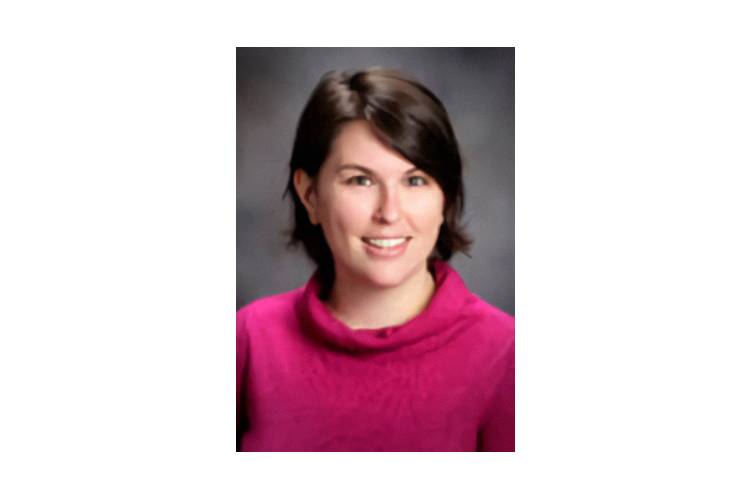 A woman in a pink sweater smiling for the camera.