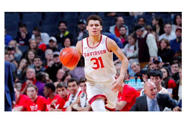 A man in white and red basketball uniform holding a ball.