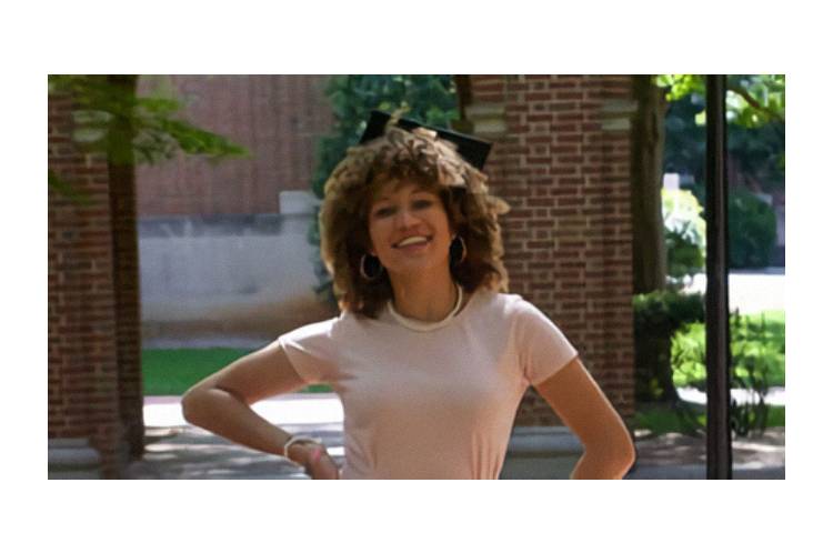 A woman with curly hair standing in front of a brick building.