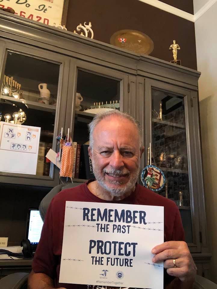 A man holding up a sign that says " remember the past protect your future ".