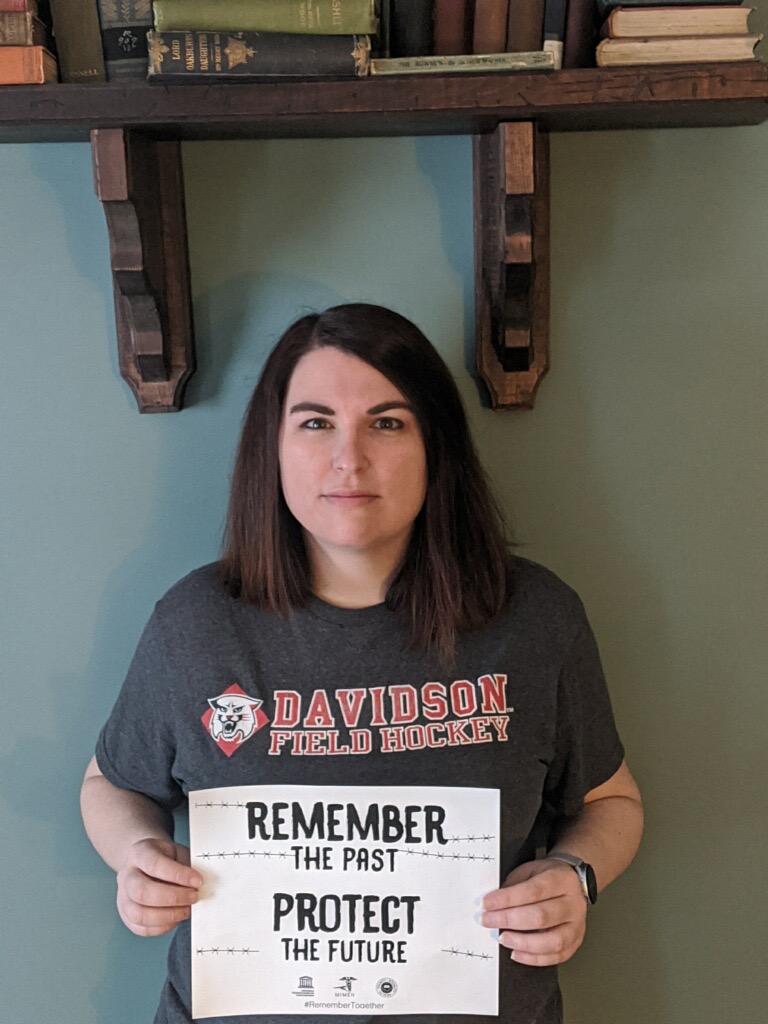 A woman holding up a sign that says remember the first.