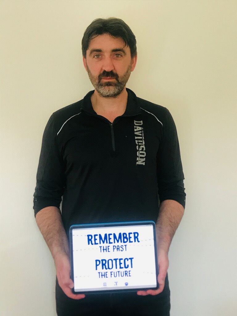 A man holding a sign that says " remember the past protect the future ".