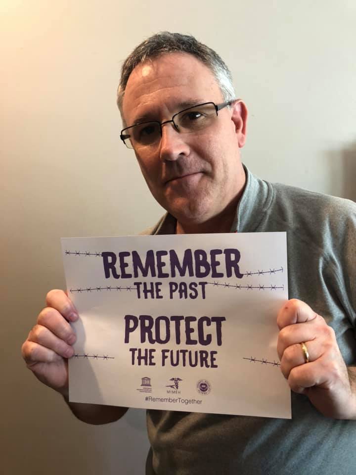 A man holding up a sign that says " remember the past protect the future ".