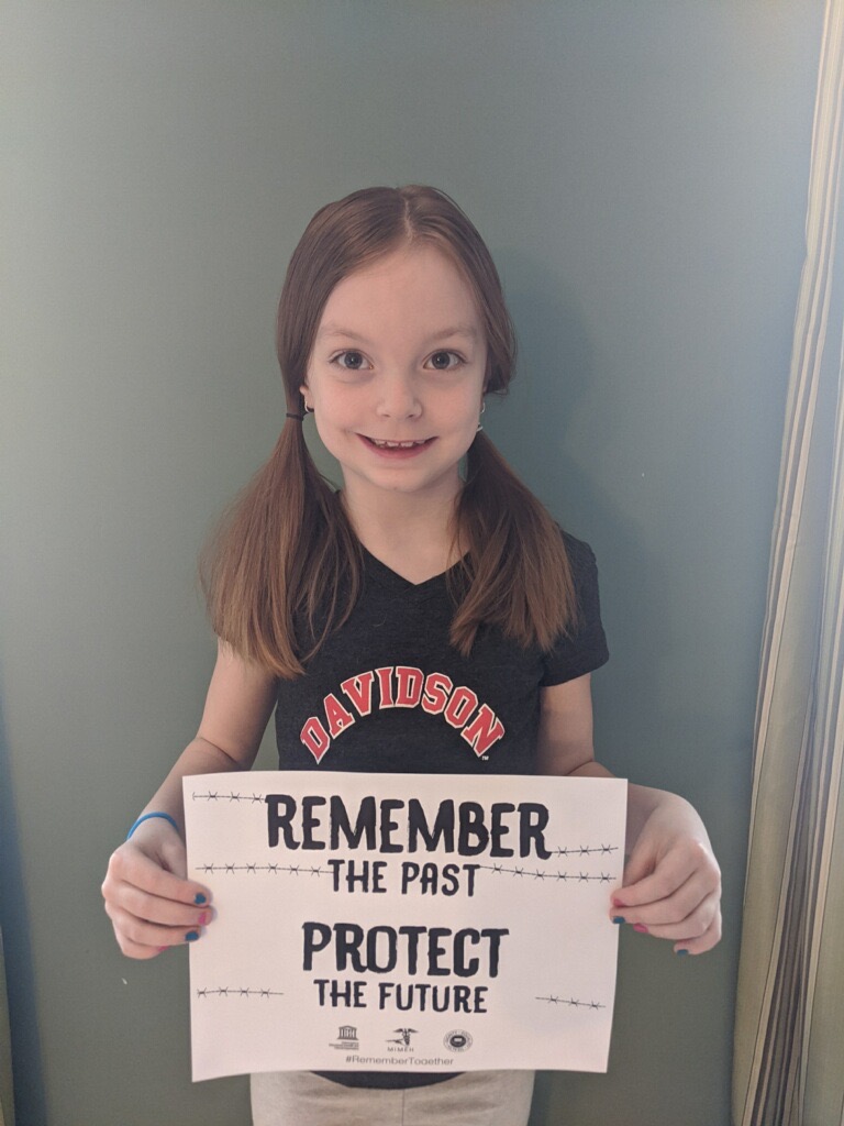 A girl holding up a sign that says " remember the past protect ".