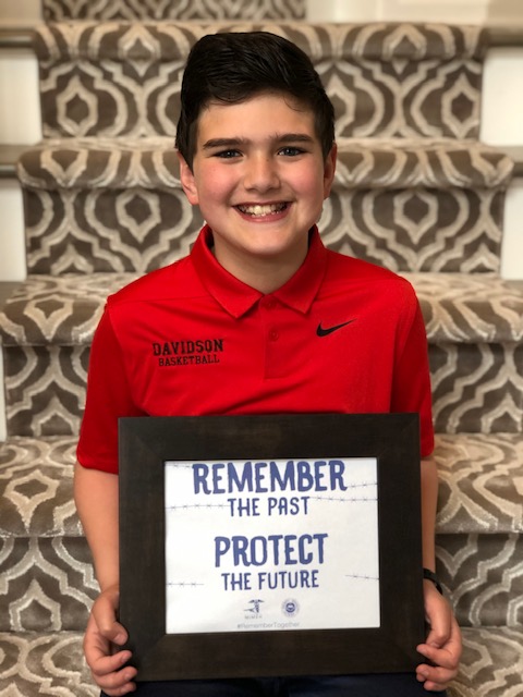 A boy holding up a sign that says " remember the past protect the future ".