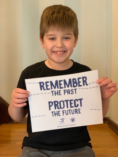 A boy holding up a sign that says " remember the past protect the future ".