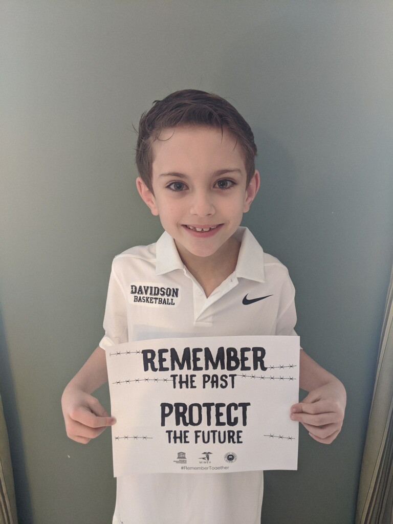 A young boy holding up a sign that says " remember the past protect the future ".