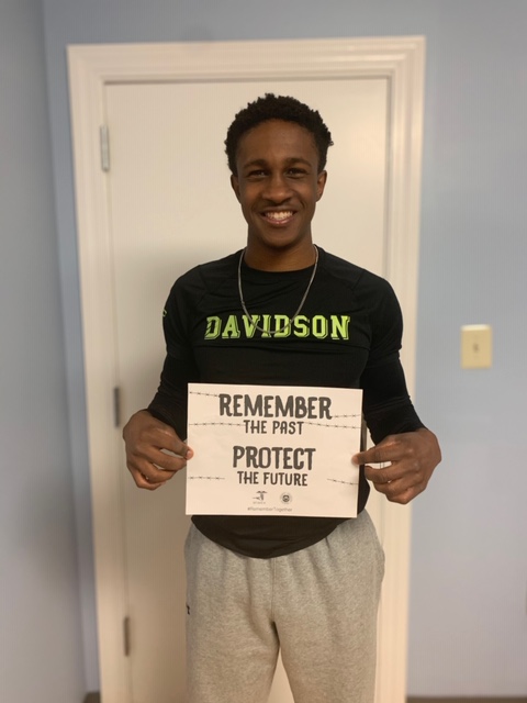 A man holding up a sign that says " remember the past protect the future ".