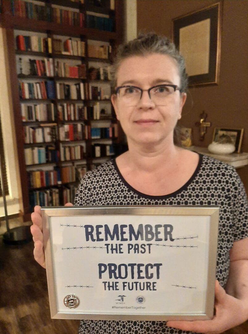 A woman holding up a sign that says " remember the past protect the future ".