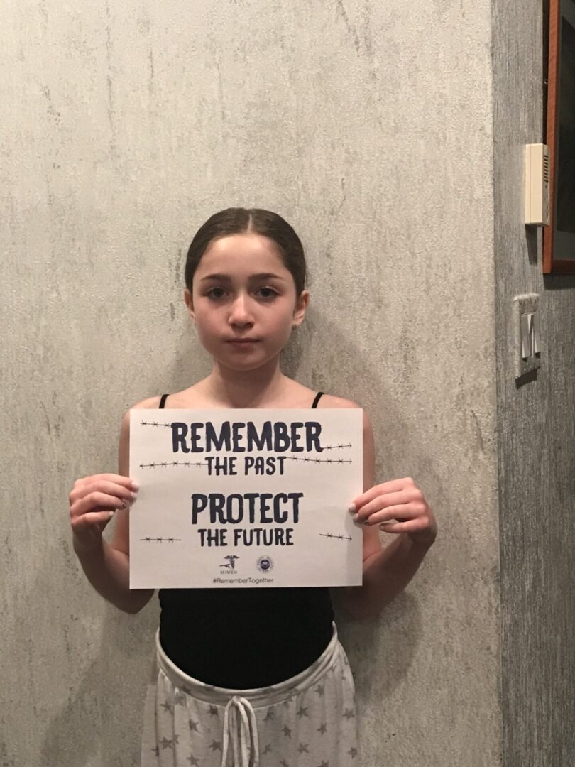 A girl holding up a sign that says " remember the past protect the future ".