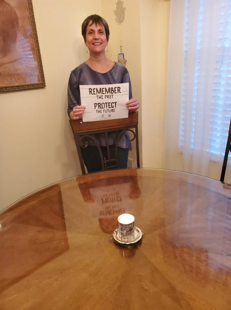 A woman holding up a sign in front of a table.