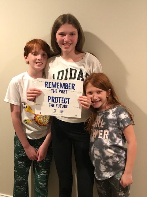 Three children holding a sign that says " remember the past protect the future ".