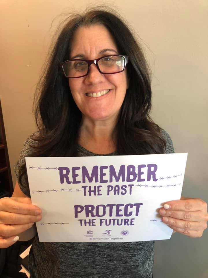 A woman holding up a sign that says " remember the past protect the future ".