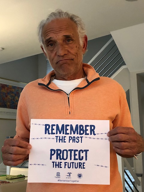 A man holding up a sign that says " remember the past protect the future ".