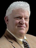 A man with white hair and wearing a suit.