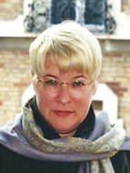 A woman with short blonde hair wearing glasses.