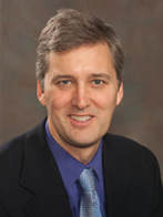 A man in a suit and tie smiling for the camera.