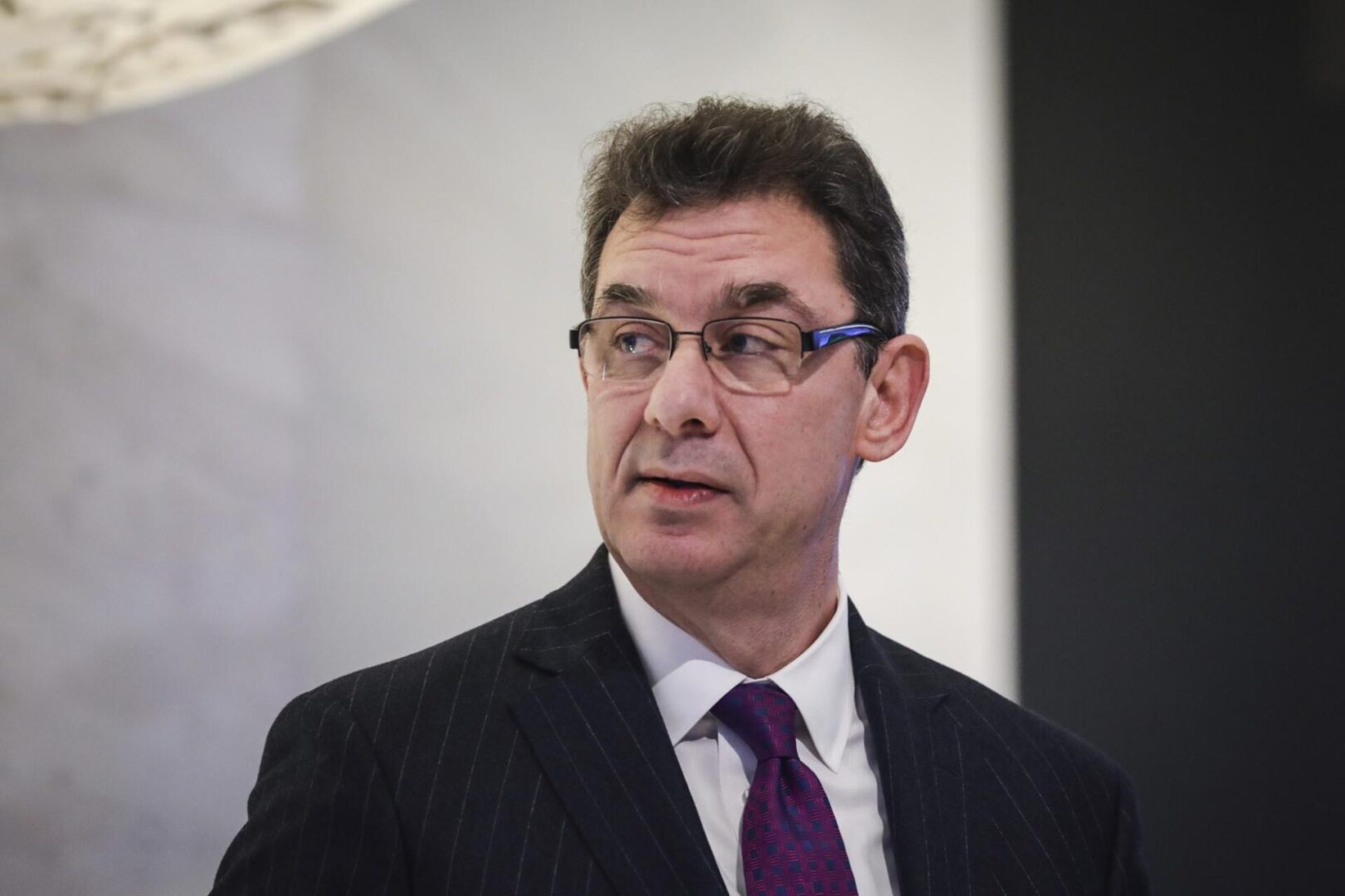 A man in suit and purple tie looking at the camera.