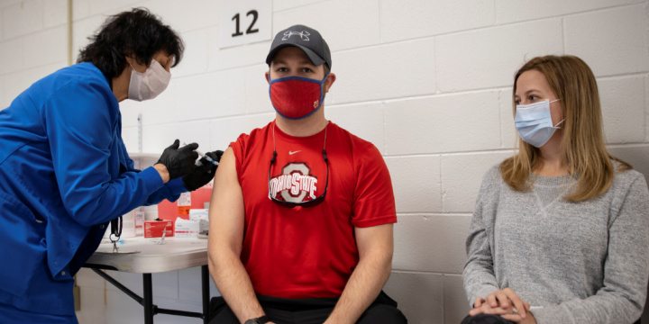 A man in red shirt wearing a face mask.