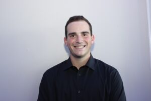 A man in black shirt smiling for the camera.