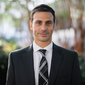 A man in suit and tie standing outside.