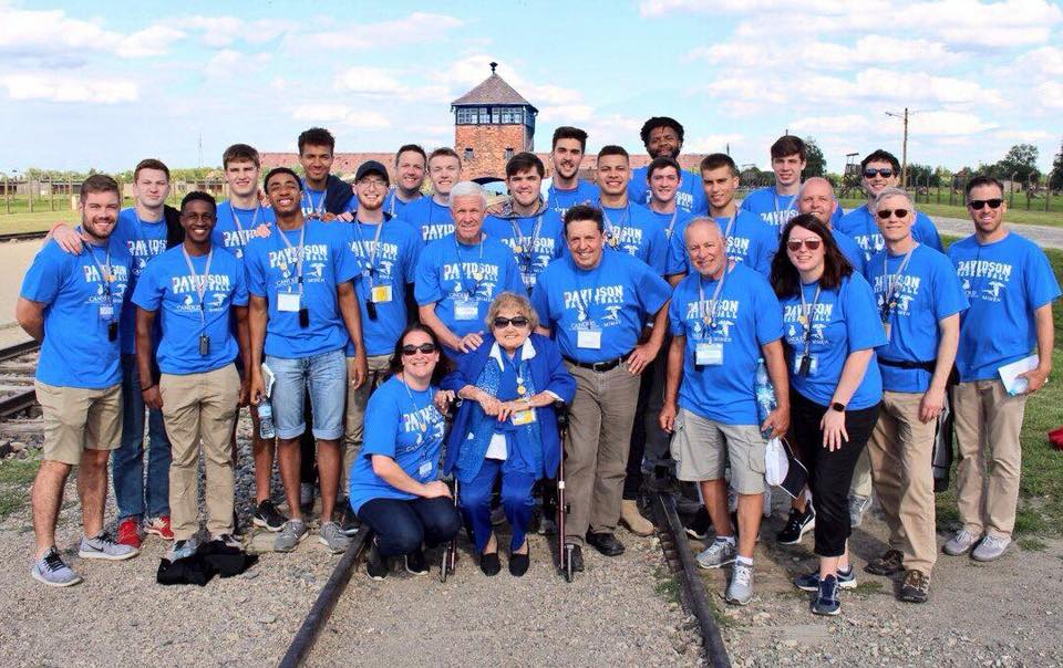 A group of people wearing blue shirts and standing on train tracks.