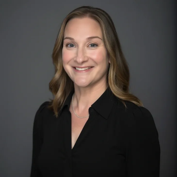 Smiling woman in black shirt, gray background.
